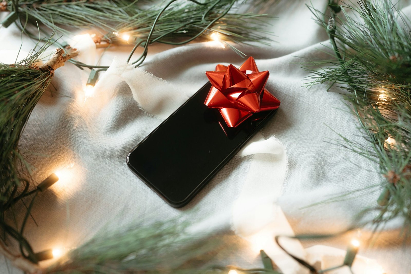 A black cell phone with a red bow on it